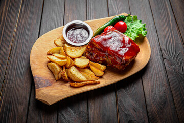 Pork loin baked in sauce with fried potatoes on dark boards background. Menu for a pub