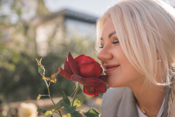 A woman is smelling a red rose. Concept of happiness and contentment, as the woman is enjoying the...