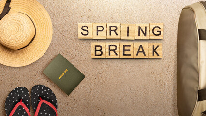 Summer break is shown using the text with wooden cubes on the sandbeach and beach bag, sandal, passport and sandal.