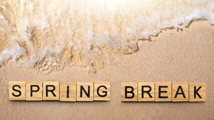 Summer break is shown using the text with wooden cubes on the sandbeach and seashore.