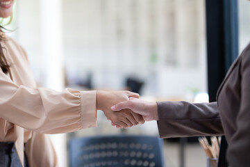 Two professionals exchange a handshake in an office environment, symbolizing agreement or greeting...