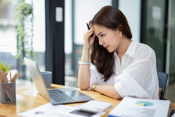 Obraz premium Concerned businesswoman in deep thought, facing work challenges while at her laptop in a busy office environment.