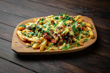 A hearty appetizer of roasted potatoes, meat and sauces on dark boards background. Menu for a pub
