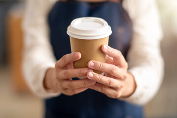 A close-up view of a person's hands gently holding a recyclable coffee cup, representing a moment...