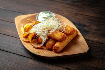 Cheese sticks with potato chips on dark boards background. Menu for a pub