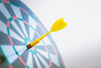 Close up yellow dart arrow hitting target center dartboard on sunset background. Business targeting...
