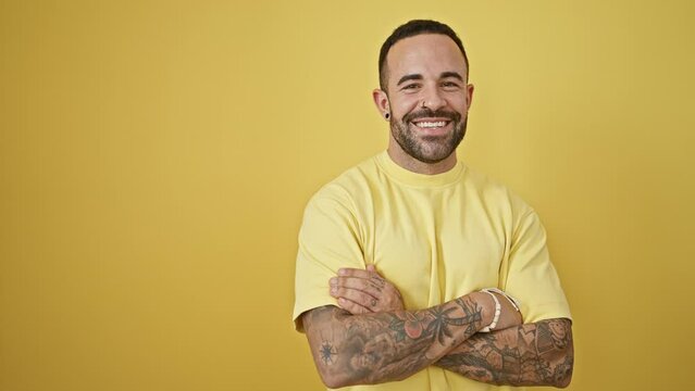 Handsome hispanic man with tattoos posing confidently against a yellow background, exuding casual style