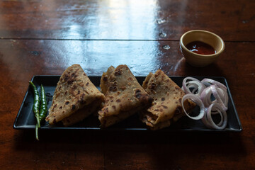 Stuffed sattu ka paratha or channa dal paratha served with condiments. Close up, selective focus. An Indian breakfast dish.  - obrazy, fototapety, plakaty