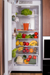 Open luxury refrigerator filled with lots of different types of food and drinks with a shelf full of fruits and vegetables.