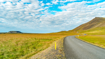 Paved Ring road and volcanic crater in Western Iceland, in Autumn colors and blue sky