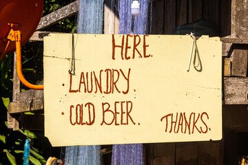 Sign "Here laundry, cold beer, thanks" in Muang Ngoi Neua village, Laos.