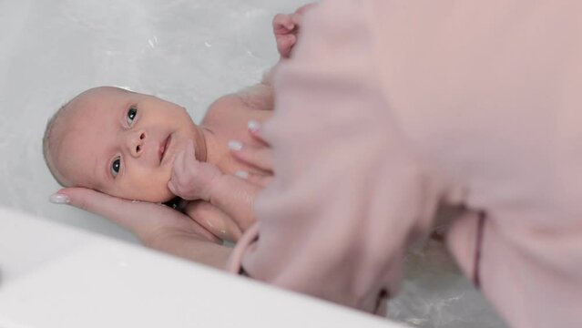 Top view of mother bathing her newborn baby, newborn baby care concept.