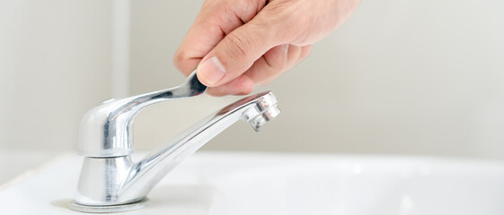 Save water. Man keeps turning off the running water in the bathroom to protect environment....