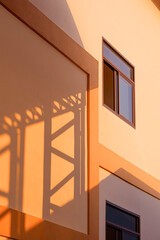 Naklejka premium Light and shadow of metal warehouse column on orange concrete wall surface of industrial office building in vertical frame, perspective side view and minimal style