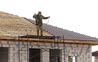 Workers install tiles on the roof of a house in winter