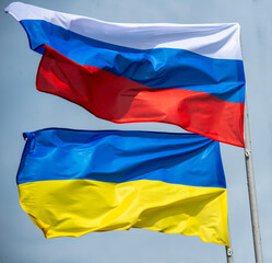 Russian and Ukrainian flags are waving with wind over blue sky. Low angle view. Dispute and conflict concept. Horizontal composition with copy space. - 787923075