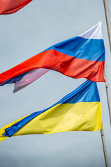 Russian and Ukrainian flags are waving with wind over blue sky. Low angle view. Dispute and conflict concept. Horizontal composition with copy space. - 787923877