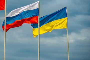 Russian and Ukrainian flags are waving with wind over blue sky. Low angle view. Dispute and conflict concept. Horizontal composition with copy space. - 787927219
