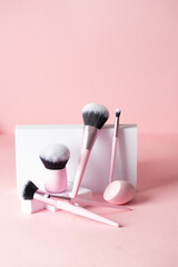 Make up powder brush, kabuki, shader etc brushes and sponge in pink color at white podium , - 787927228