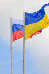 Russian and Ukrainian flags are waving with wind over blue sky. Low angle view. Dispute and conflict concept. Horizontal composition with copy space. - 787927676