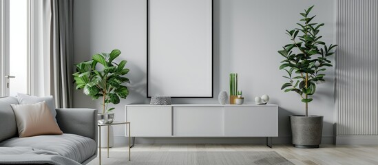 A real photograph of a simple living room interior showing a poster displayed above a white cabinet with a plant next to a grey sofa.