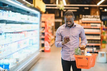 African man shopping at supermarket. Handsome guy holding shopping basket