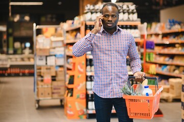 African American Man Talking On Cellphone Chatting While Shopping Groceries In Supermarket
