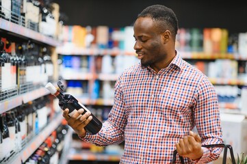 African American man in grocery store buying wine