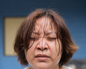 A woman closes her eyes because sweat is flowing into her eyes.