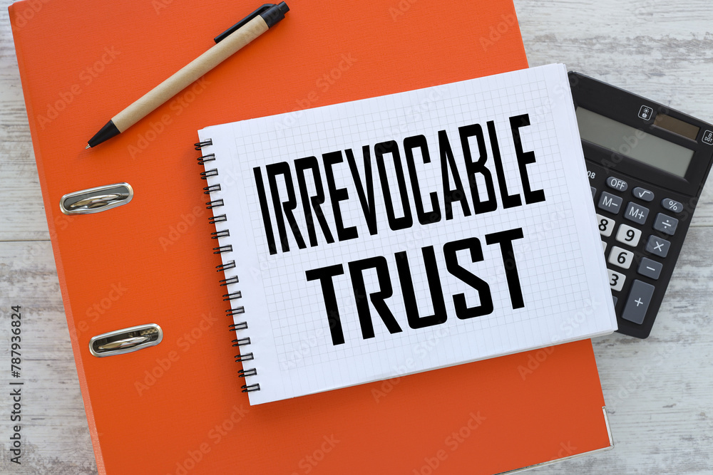 Aufkleber irrevocable trust notepad on orange folder. text on the table