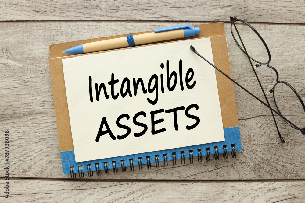 Poster intangible assets . glasses on a notepad. top view of text