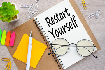 glasses lie on a notepad. text on the page. bright stickers RESTART YOURSELF