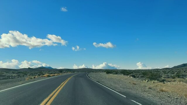 Open Road in the Desert, A deserted highway stretches into the horizon under a vast blue sky with fluffy clouds.