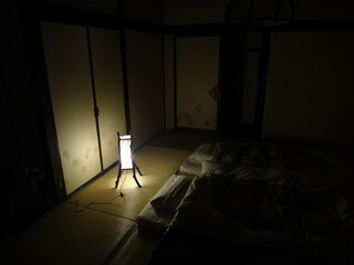 Japanese darkened bedroom interrior with tatami mat and two futon beds illuminated with small lamp