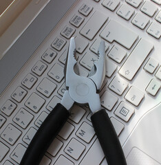 PC Support Concept Image. Metal Pliers On Laptop Keypad Closeup View
