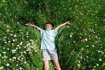 Caucasian boy lying on grass with flowers in spring