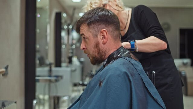Aesthetic Excellence: Woman Hairdresser Demonstrating Expertise with Clippers on a Man's Hair in a Salon, Promoting Beauty and Image Enhancement. High quality 4k footage