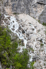 Boka waterfall in Slovenia, near Bovec. Easy trekking nature trail in the forest with the view of the immense waterfall overhanging the mountains visible from the road, long exposure photography.