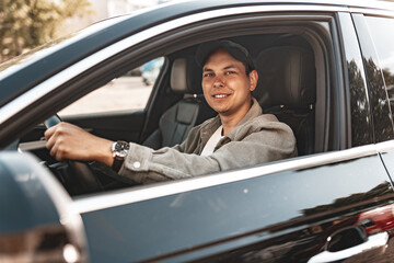 Young smiling man sitting in a car with open window