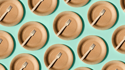 Top view of paper utensils, plate and wooden cutlery on a blue background. Eco friendly pattern,...