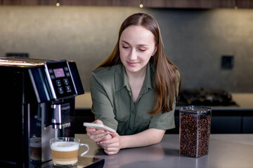 Female controlling coffee machine with phone at home. Smart home concept