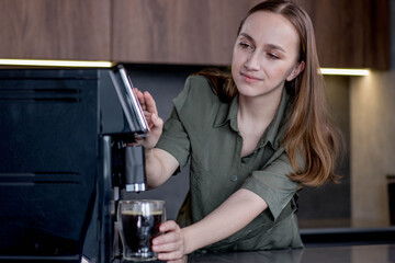 Woman preparing a fresh coffee with a coffee maker machine. Coffee blender and household kitchen appliances for makes hot drinks
