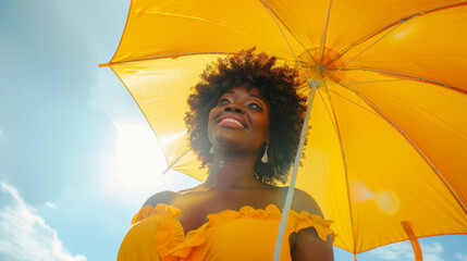 Happy black afro american woman with sunny blue sky holding a yellow umbrella or sunshade to protect her skin from sun light with return of warm days