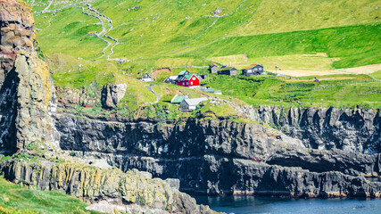 Mykines, Faroe Islands. Panoramic view of Mykines island village, bird watching destination for puffins. Traditional houses with turf roofs, cliffs and ocean