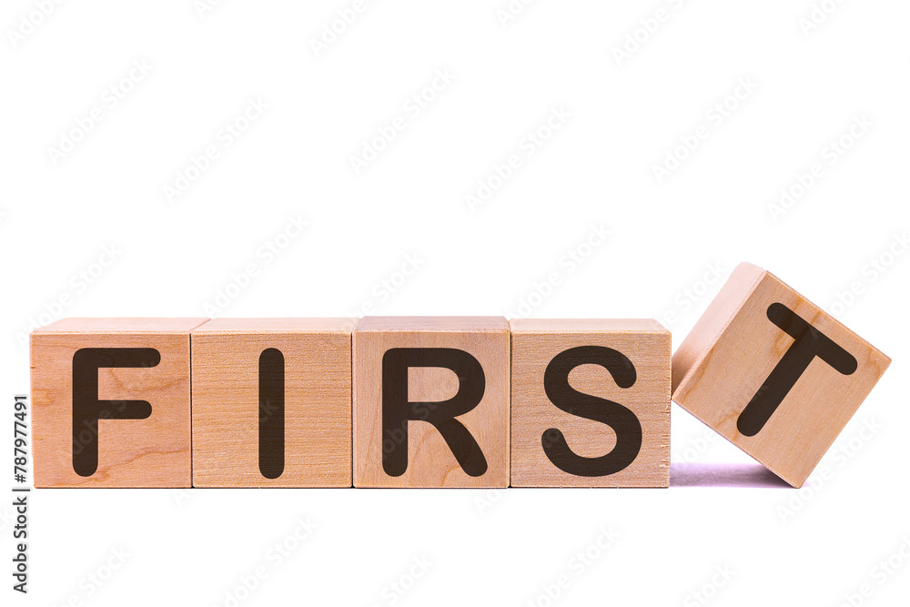 Fototapete Word FIRST is made of wooden building blocks lying on the table and on a light background. Concept.
