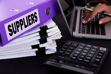 Text, word Suppliers is written on a folder lying on documents on an office desk with a laptop and a calculator. Business concept.