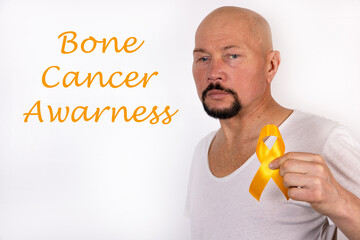 A man in light clothing with a yellow ribbon in his hand as a sign of awareness of Bone cancer