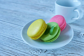 Colorful macaroons on a white plate on a wooden background