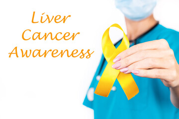 Liver cancer awareness concept. A doctor in blue clothes with a yellow ribbon in her hand, as a...