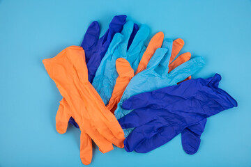 Blue, orange disposable medical, surgical gloves on a blue background. Medical concept, symbol.